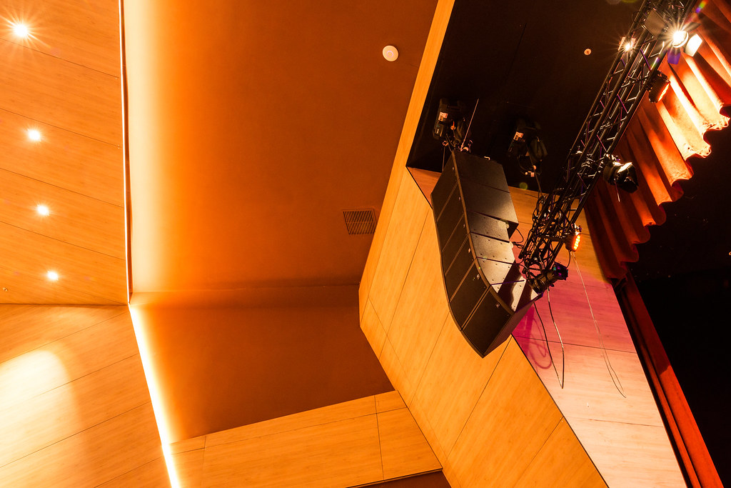 Revolutionando el Sonido: Innovaciones en Amplificadores de Estado Sólido 1 Una vista interior de un teatro con paredes y suelos de madera, y un escenario con cortinas rojas, perfecto para un artículo sobre innovaciones en amplificadores de estado sólido.