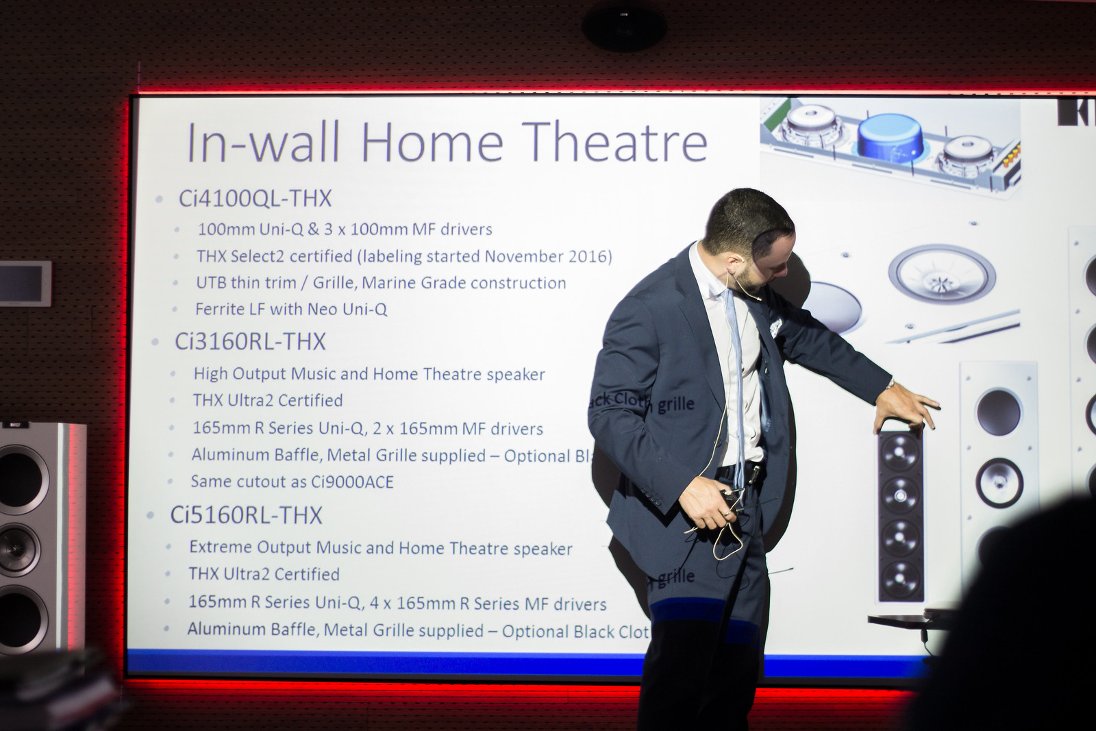 Mastering Lavalier Mics: Placement, Audio Levels & Top Tips 1 Expert presenter discussing in-wall home theatre systems with detailed diagrams and specifications on the screen, ideal for an article on ‘Mastering Lavalier Mics: Placement, Audio Levels & Top Tips’. Presentador experto discutiendo sistemas de cine en casa empotrados en la pared con diagramas detallados y especificaciones en la pantalla, ideal para un artículo sobre ‘Dominando los micrófonos de solapa: ubicación, niveles de audio y consejos principales’.