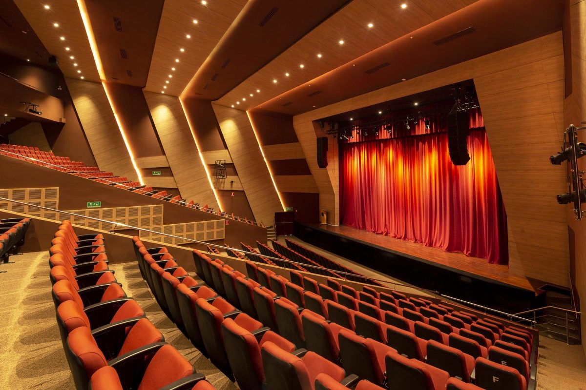 31941059808_8a3f893c7c_h A grand interior of a modern theater with a large stage adorned with a red curtain, polished wood panels on walls and ceiling, and rows of comfortable, red upholstered seats, optimized for an article on ‘Maximizing Acoustics: The Vital Role of NRC in Sound Design’. Un gran interior de un teatro moderno con un gran escenario adornado con una cortina roja, paneles de madera pulida en paredes y techo, y filas de cómodos asientos tapizados en rojo, optimizado para un artículo sobre ‘Maximizando la Acústica: El Rol Vital del NRC en el Diseño del Sonido’.