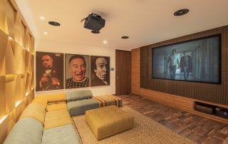 Optimizando la Acústica en Espacios Complejos con Tecnología Avanzada 5 Elegantly designed home theater room with a large projector screen and geometrically shaped acoustic panels, optimized for an article on ‘Optimizing Acoustics in Complex Spaces with Advanced Technology’.