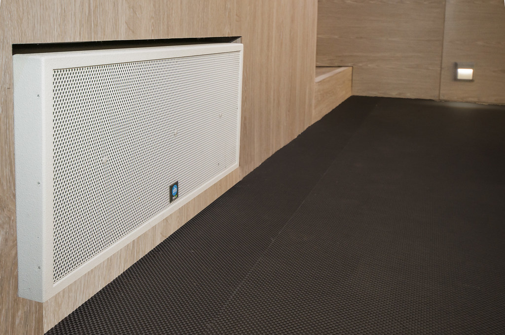 Revolutionando el Sonido: Innovaciones en Amplificadores de Estado Sólido 3 Una visión del interior moderno con un panel perforado blanco en una pared de madera, ilustrando la integración de la tecnología en los sistemas de sonido.