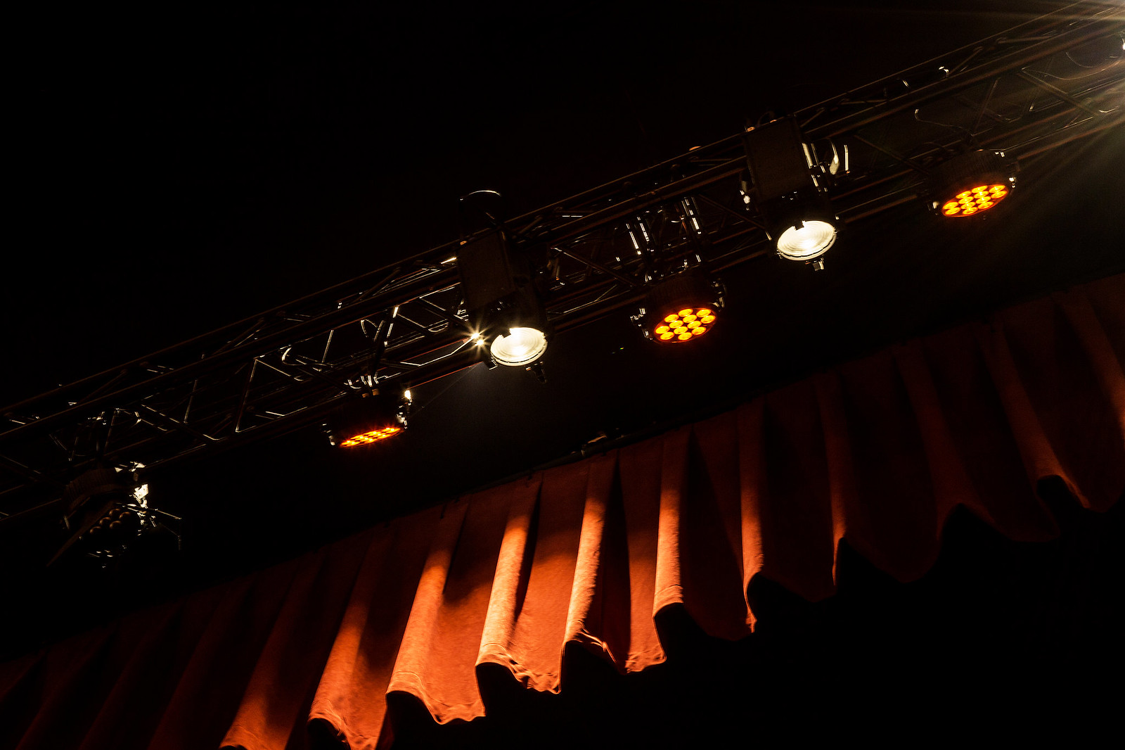 Technical Design in Performance Spaces 1 Stage lights illuminating a dark, wavy curtain, creating a dramatic and intense atmosphere, perfect for ‘Technical Design in Performance Spaces’. Luces de escenario iluminando una cortina oscura y ondulada, creando un ambiente dramático e intenso, perfecto para ‘Diseño Técnico en Espacios de Actuación’.