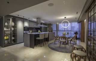 Maximizando la Eficiencia del Hogar: La Guía Definitiva para el Control de Iluminación y Automatización 5 Spacious, well-lit modern kitchen and dining area with sleek gray cabinetry, a large island, and a round dining table, optimized for an article on ‘Home Acoustics: Simple Tips to Enhance Your Space’s Sound’.