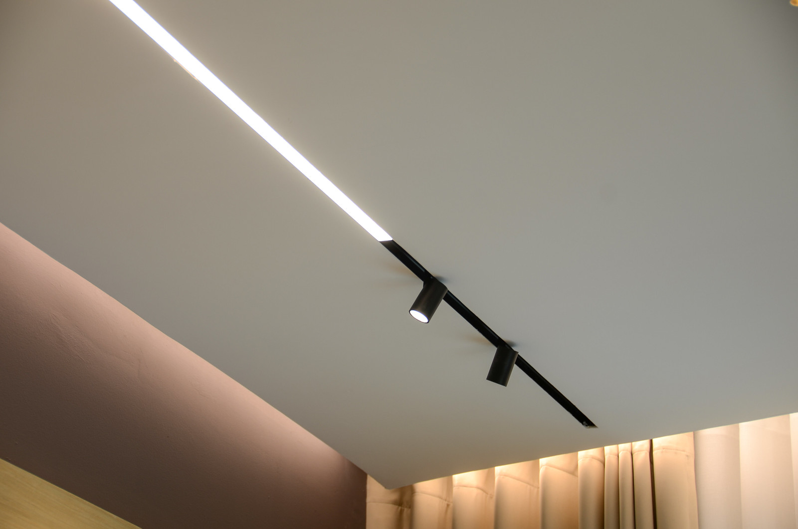 Mejorando las Experiencias de Audiovisual: El Papel Crucial del Diseño de Iluminación 1 Configuración interior elegante que muestra una moderna disposición de iluminación, con un enfoque en una luz lineal brillante que proyecta un intenso resplandor blanco, acentuando el contraste entre el techo y la pared.