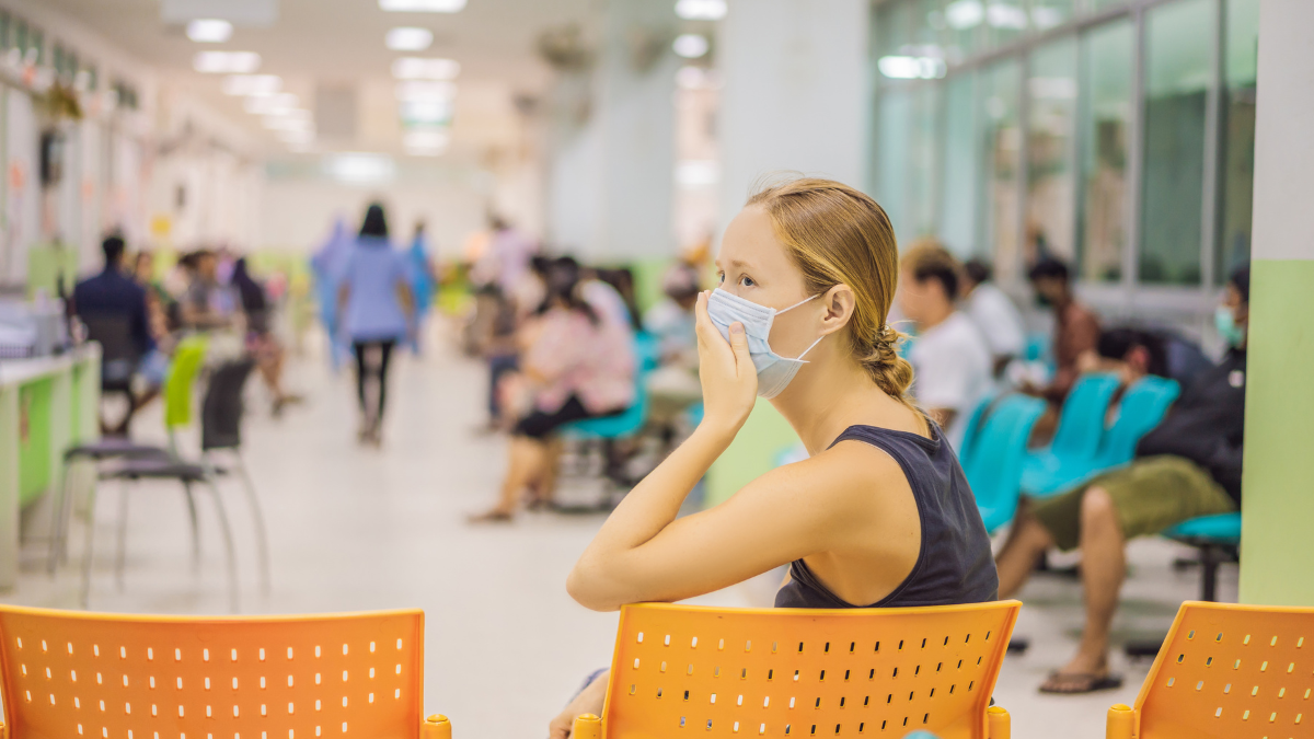 Optimización de la Acústica en Espacios de Atención Médica para el Confort del Paciente 1 Personas sentadas en una sala de espera bien iluminada con sillas naranjas y verdes, siguiendo precauciones de salud, para un artículo sobre la optimización de la acústica del espacio de atención médica para la comodidad del paciente.