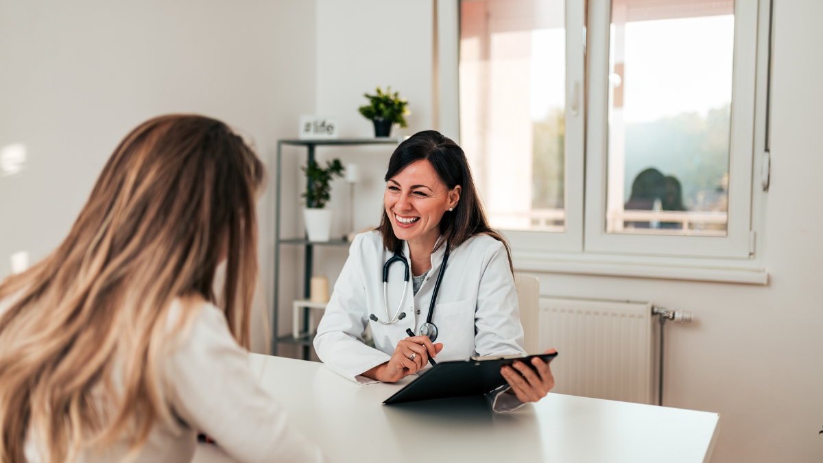 Doctor consulting with a patient in a well-lit, acoustically optimized healthcare space, for an article on optimizing healthcare space acoustics for patient comfort. Médico consultando con un paciente en un espacio de atención médica bien iluminado y acústicamente optimizado, para un artículo sobre la optimización de la acústica del espacio de atención médica para la comodidad del paciente.