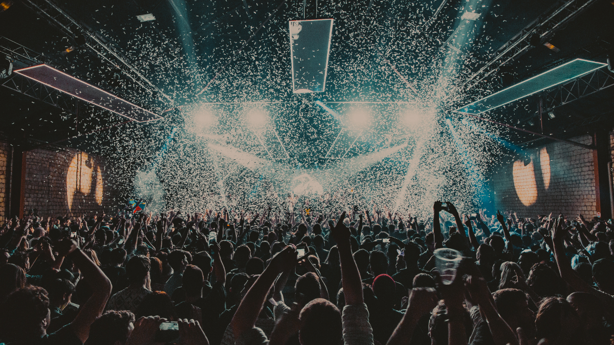 Mastering Audiovisual Design for Memorable Events and Shows 1 A lively crowd at a concert with hands raised, illuminated by bright lights and confetti, reflecting the excitement of memorable events and shows. Una multitud animada en un concierto con las manos levantadas, iluminada por luces brillantes y confeti, reflejando la emoción de eventos y espectáculos memorables.